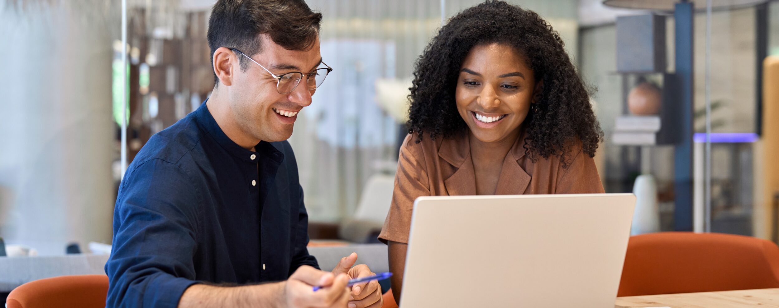 Male and female smiling looking at laptop screen