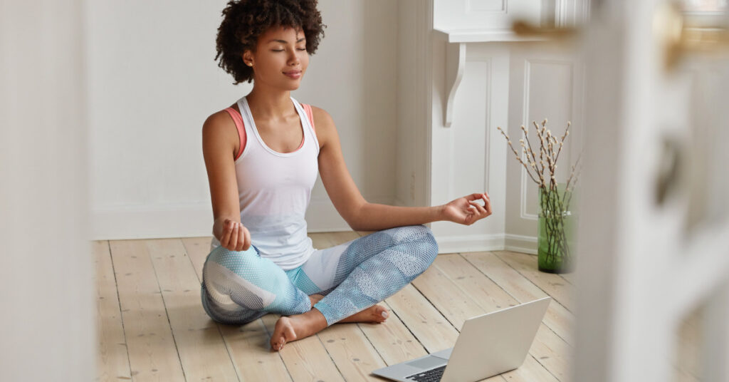 Women meditating with laptop on floor