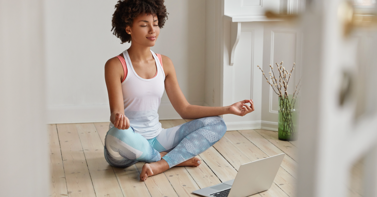 Women meditating with laptop on floor