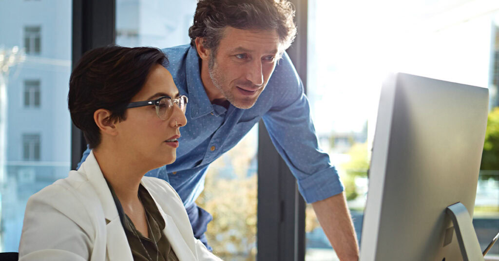 A woman and man looking at desktop computer.