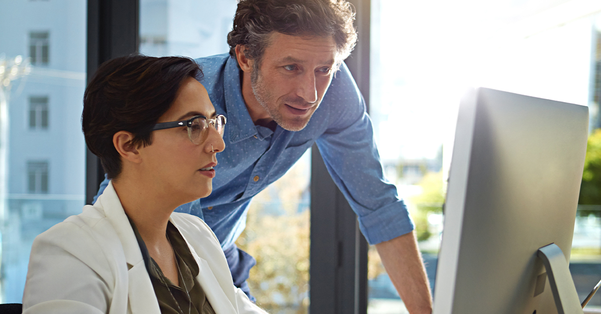 A woman and man looking at desktop computer.
