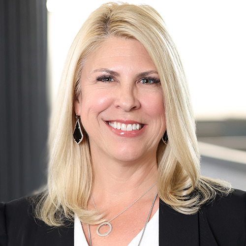 Professional headshot of a woman with long blonde hair in a dark blazer