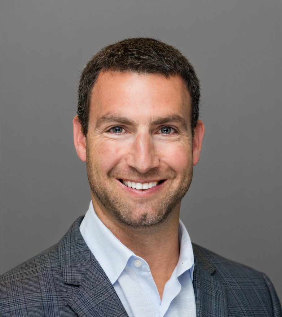 Professional headshot of a young man with dark hair in a gray suit jacket