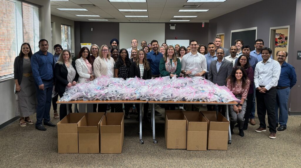 Group photo of Claritev employees gathered around a table of packed care kits