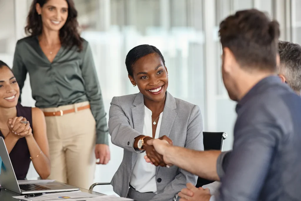 Three colleagues exchanging a handshake at an office meeting