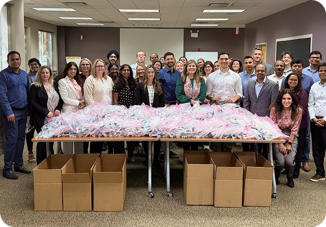Group of Claritev employees gathered around a table piled with packed care bags ready for donation