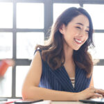 women smiling sitting at desk on computer